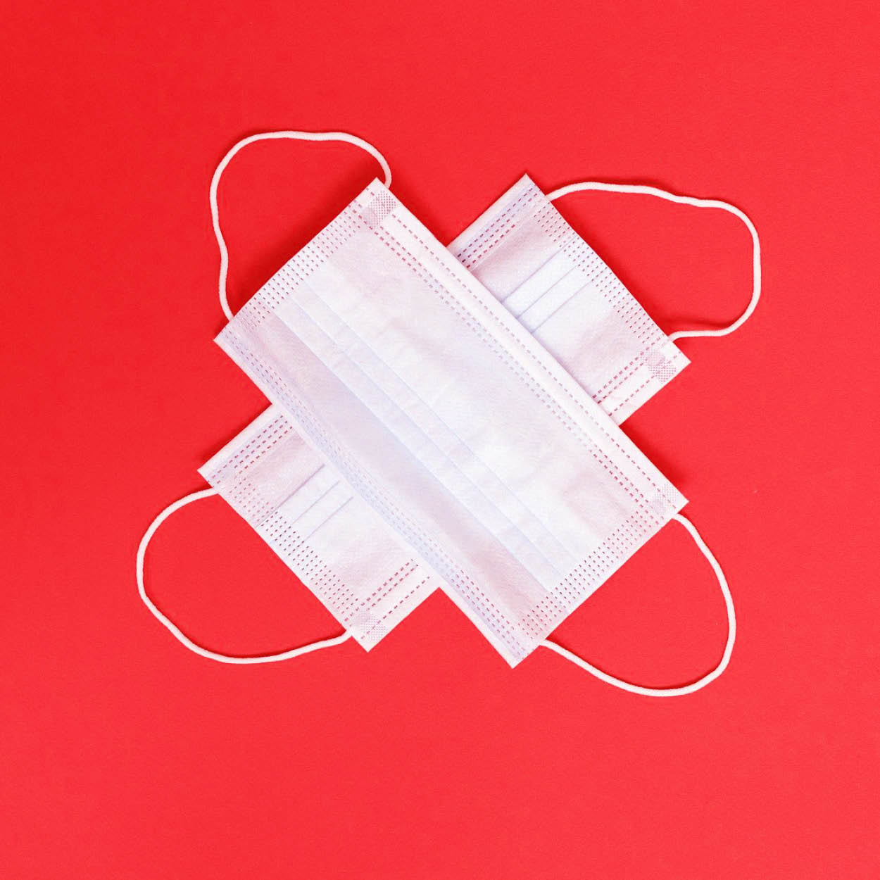 Zdjęcie przedstawia maseczki higieniczne znajdujące się na czerwonym tle.