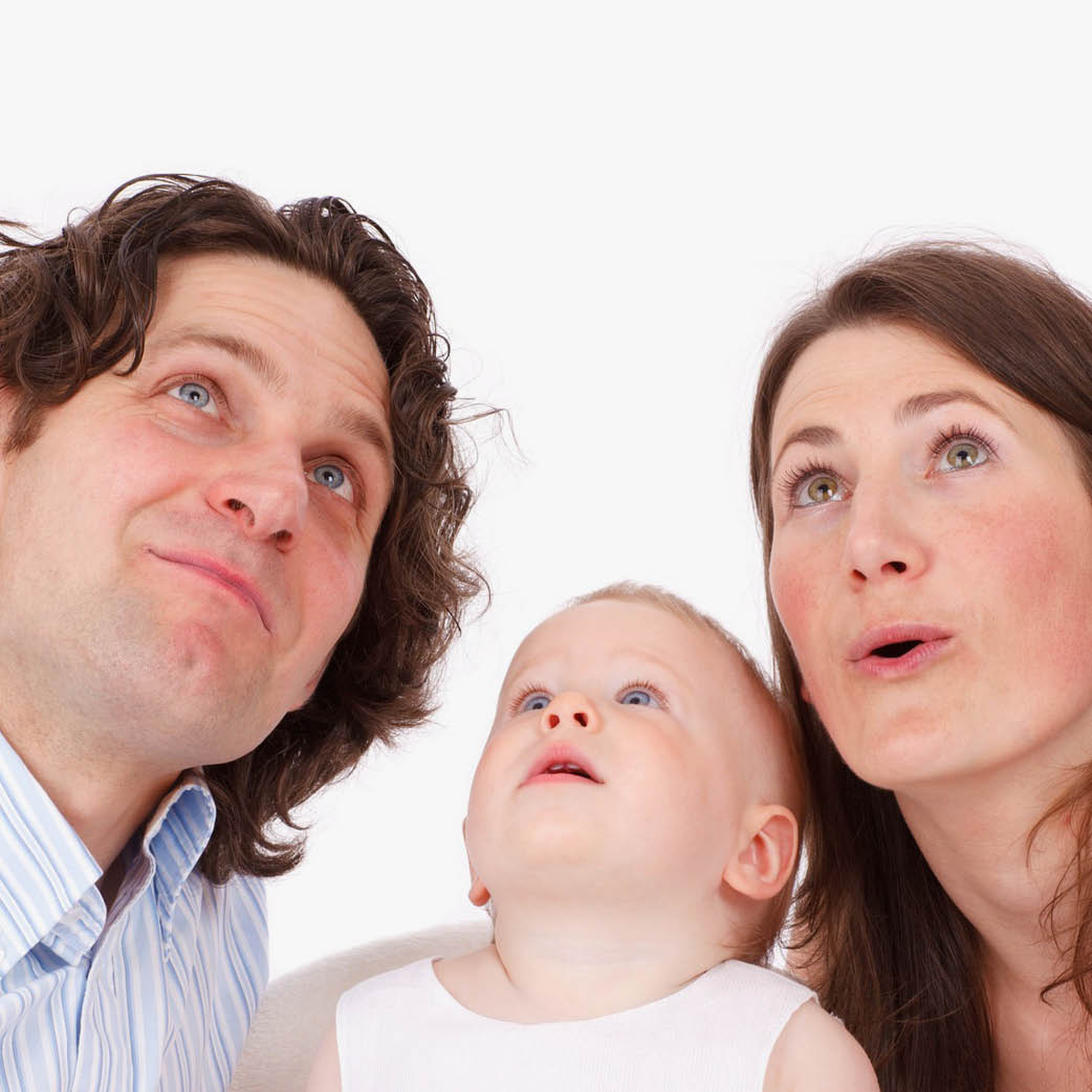 Zdjęcie przedstawia rodziców z bobasem, cała trójka patrzy do góry.