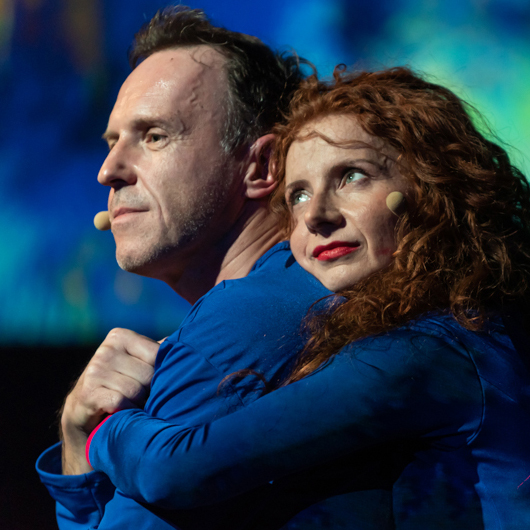 Zdjęcie przedstawia aktorów, kobieta i mężczyzna w objęciach.