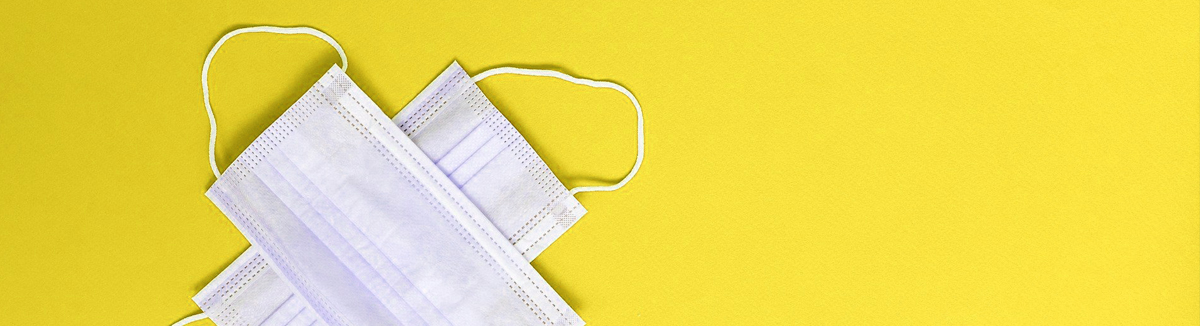 Zdjęcie przedstawia maseczki higieniczne znajdujące się na żóltym tle.