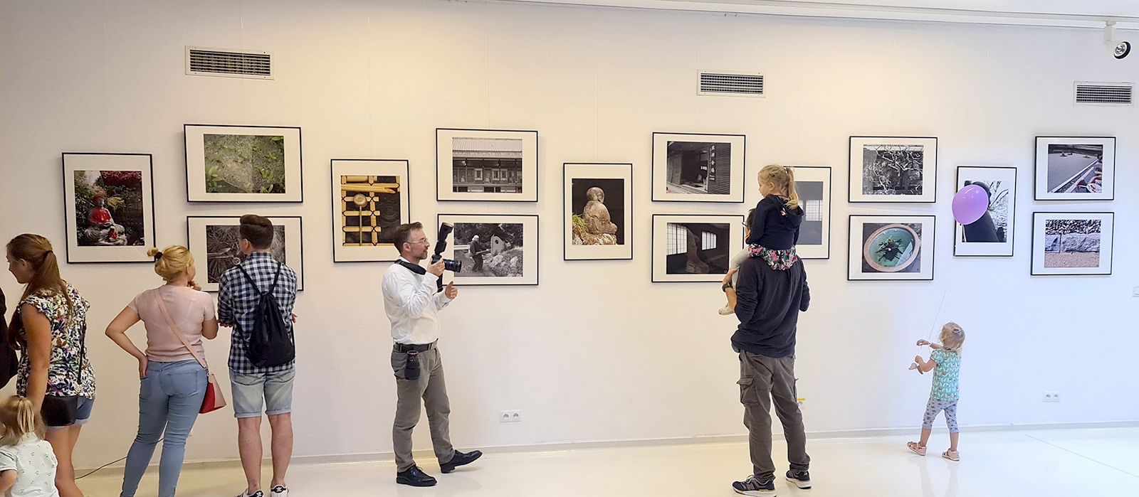 Widok Galerii w SDK podczas wernisażu wystawy ZEN, na ścianach prezentowane są fotografie wokół zwiedzający ludzie.