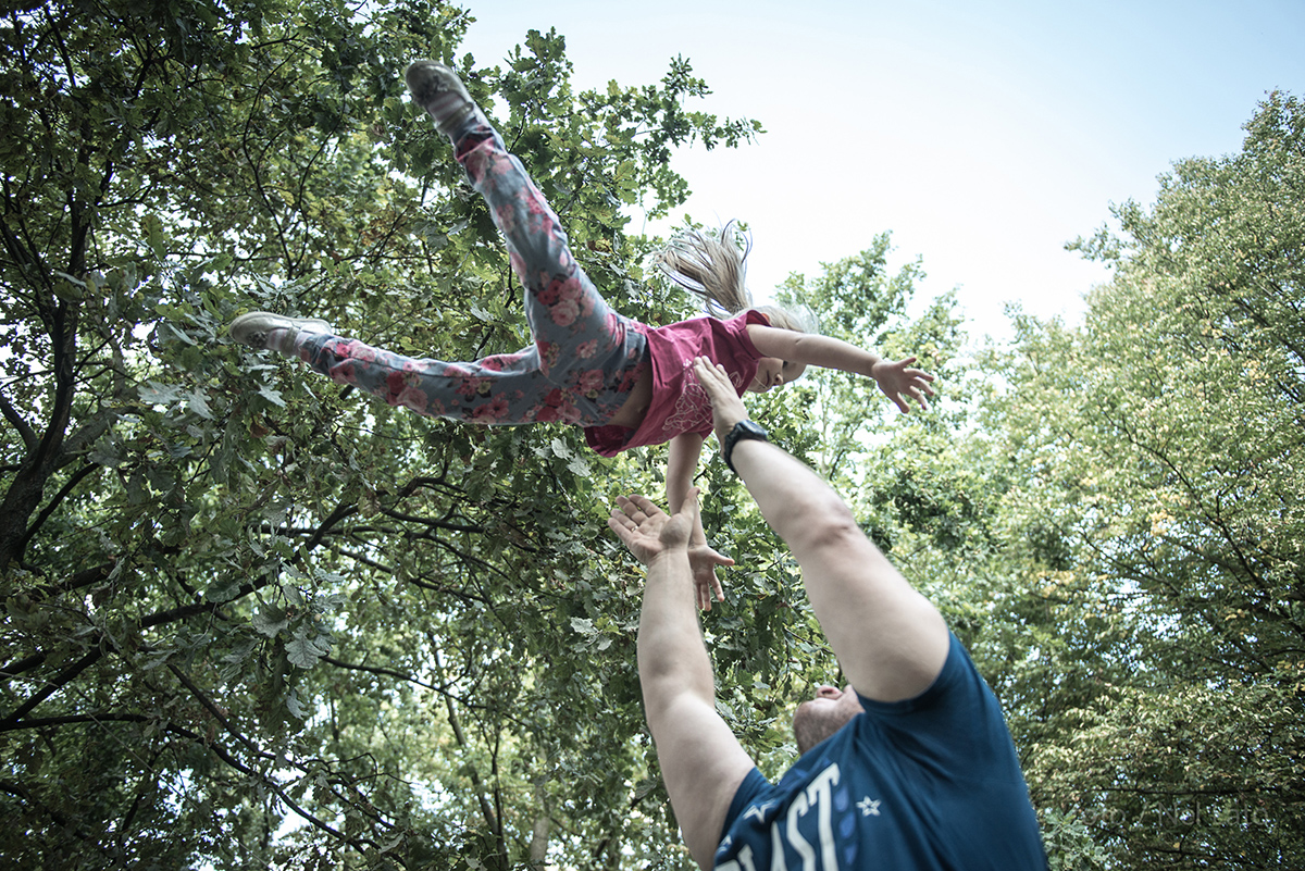 Zdjęcie przedstawiające mężczyzny przedramiona,  które chwytają  małą dziewczynkę. 