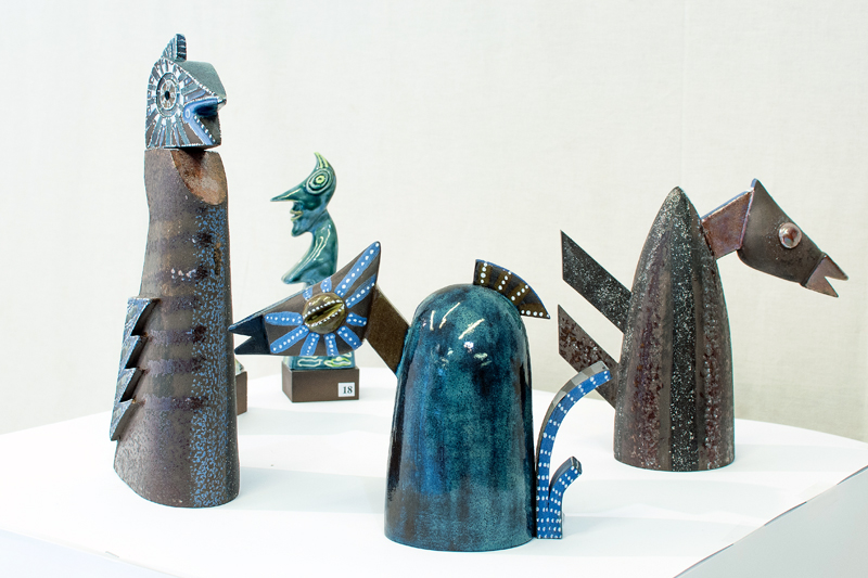 Grupa ceramicznych rzeźb stylizowanych unikatowych ptaków. Ceramika utrzymana w gamie brązów i błękitów.