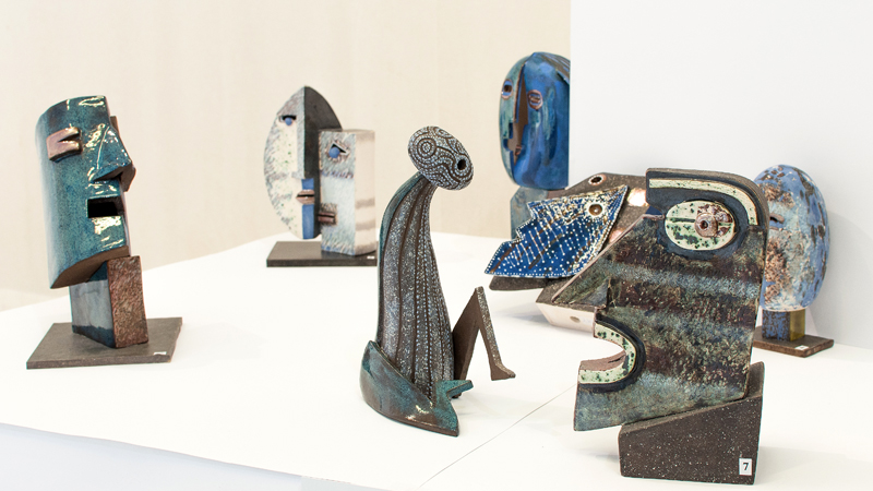 Zdjęcie fragmentu ekspozycji rzeźb ceramicznych Marii Kostrzewskiej-Baron. Na pierwszym planie od lewej: rzeźba głowy, siedzącej postaci i profilu twarzy.