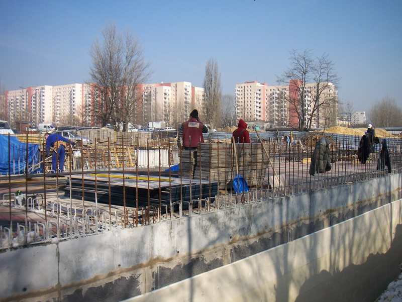 Na zdjęciu budowa nowej siedziby SDK. Widoczne betonowe elementy budowy oraz pracownicy budowy. W tle osiedle Służew nad Dolinką.