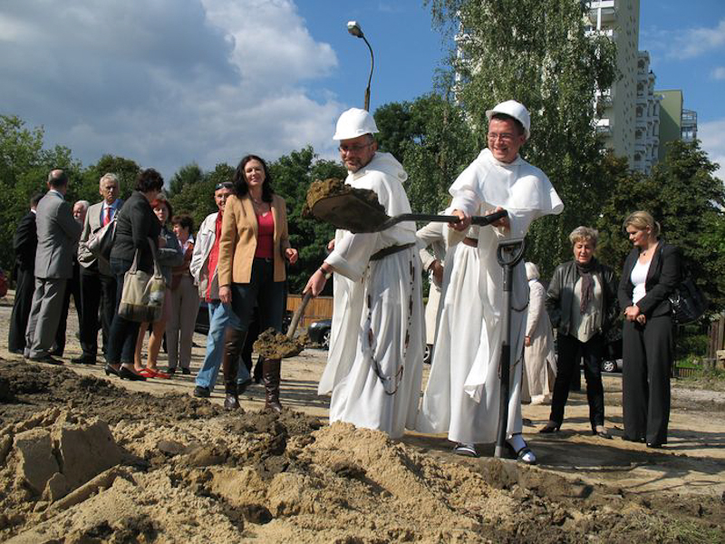 Na zdjęciu księża z zakonu o. Dominikanów podczas symbolicznego wbicia łopaty. W tle pozostali goście wydarzenia. 