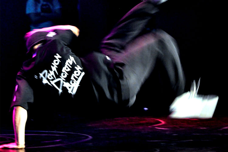 Na zdjęciu widoczny jest tancerz break dance w akrobatycznej pozie. 