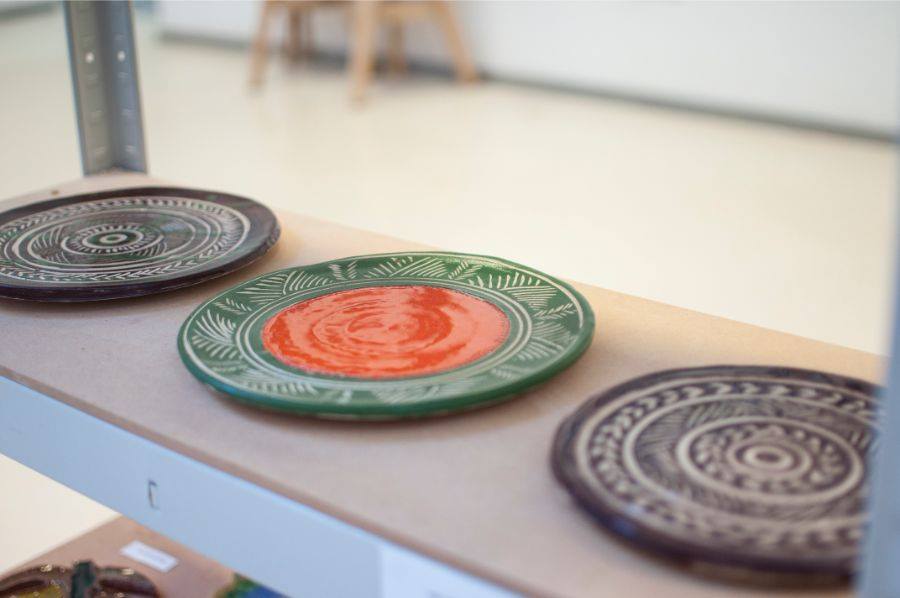 Zdjęcie promocyjne pracowni. Na Zdjęciu widoczne są prace uczestników zajęć ceramicznych. Kolorowe, ceramiczne talerze.