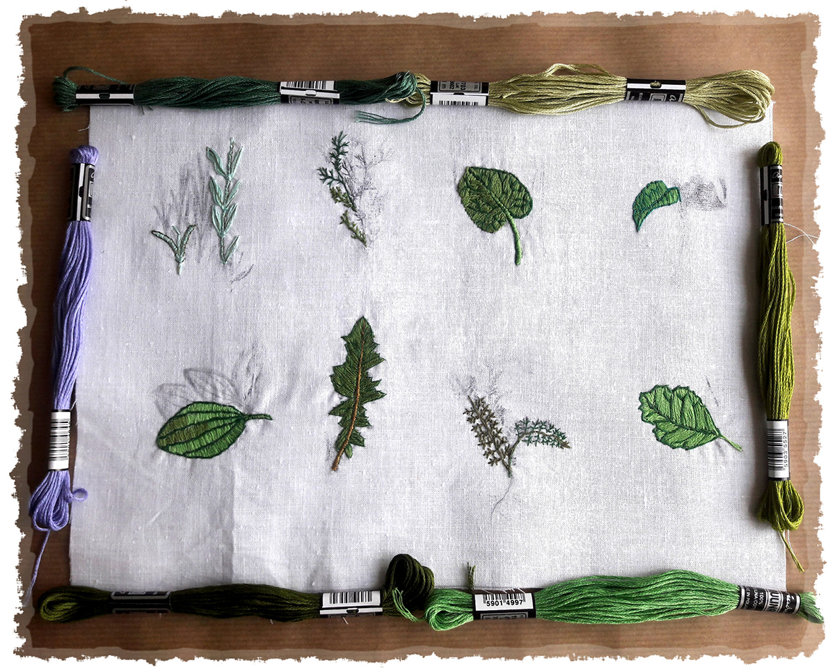 Zdjęcie promocyjne pracowni.  Na zdjęciu próbki haftu oraz przygotowane do szkicowania elementy roslinne. Dookoła płótna rozłożona mulina.