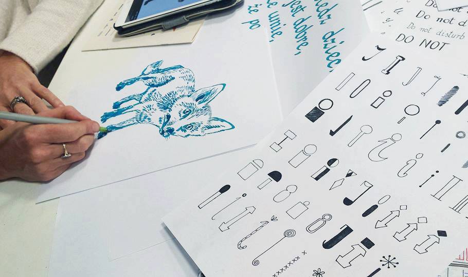 Na zdjęciu widoczne dłonie rysujące ilustrację lisa za pomocą cienkopisu.