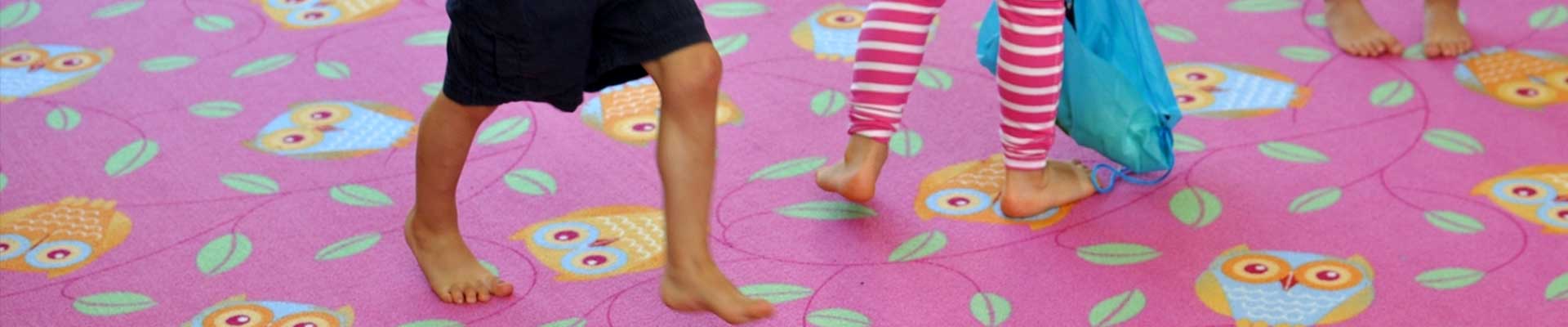 Na zdjęciu widać częściowo trójkę małych dzieci bawiących się na kolorowej podłodze. Fot. SDK