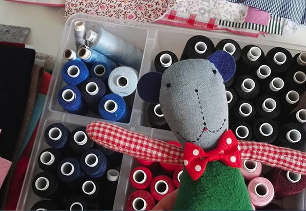 Zdjęcie promocyjne pracowni. Na zdjęciu pacynka leżąca na zestawie nitek do szycia.