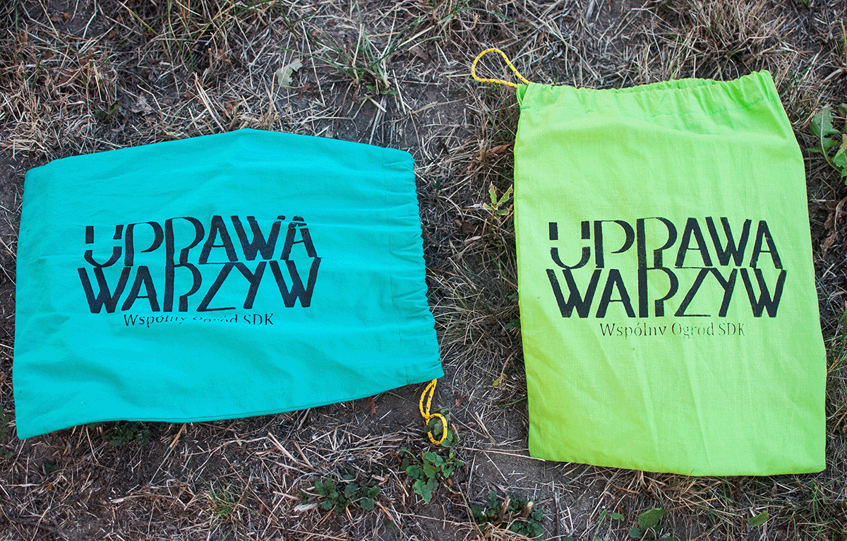 Zdjęcie promocyjne pracowni. Na zdjęciu dwa kolorowe worki ułożone na ziemi. Na workach napis "uprawa warzyw"