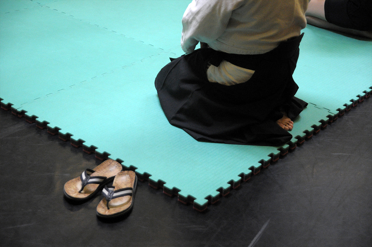 Na zdjęciu widoczne są dwie postacie zawodników aikdio w pozycjach walki. Zdjęcie zrobione z góry, znad zawodników.