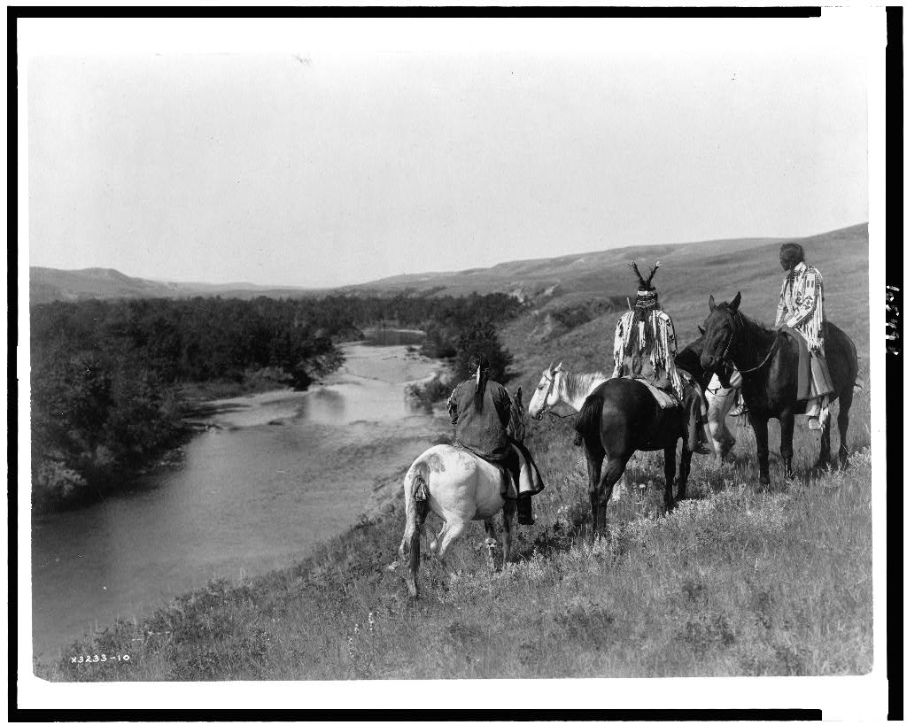 Edward S. Curtis, Indianie na wzgórzu, około 1910, ze zbiorów Biblioteki Kongresu USA, na zdjęciu widać kilku indian na koniach, są odwróćeni tyłem do fotografa, patrzą w dal, na wgrzórze i rzekę po lewej stronie zdjęcia.