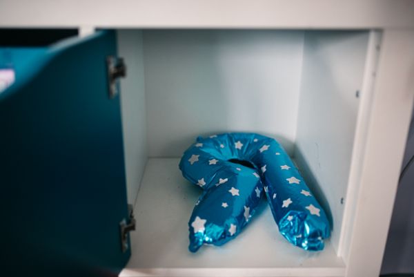 Zdjęcie pokazuje balon w kształcie litery R o kolorze niebieskim w białe gwiazdki leżący w otwartej półce. Fot. Agnieszka Mocarska