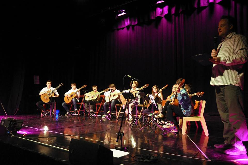 Zdjęcie promocyjne pracowni Na zdjęciu widoczna jest grupa gitarzystów na scenie.