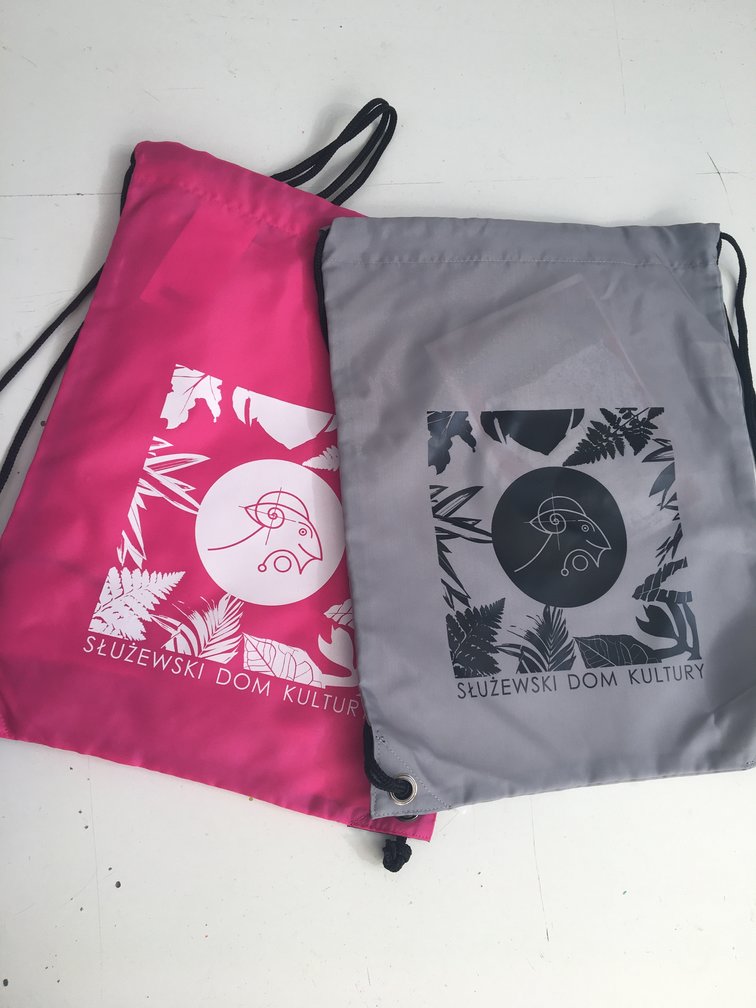 Na zdjęciu widać dwa worki widziane z góry. Jeden jest w kolorze fuksji z białym ornamentem, drugi - szary z czarnym ornamentem. Grafiką obu worków to koza, wokół której rozłożone są elementy botaniczne.
