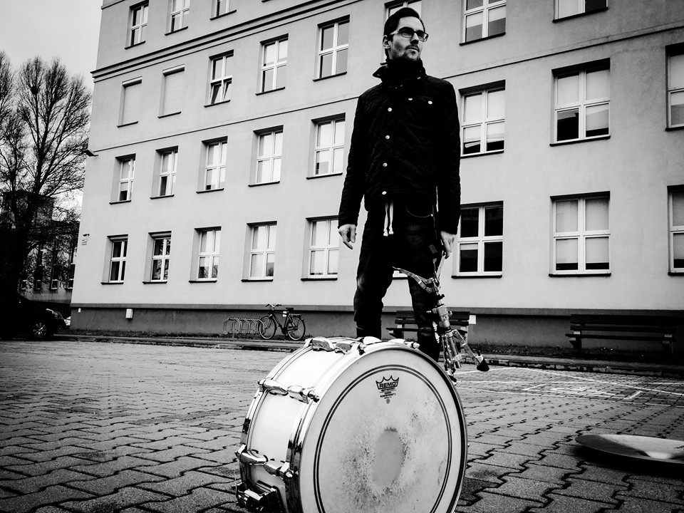 Zdjęcie prezentujące sylwetkę instruktora warsztatów Na zdjęciu na pierwszym planie widoczny jest bęben perkusji, na drugim planie widzimy sylwetkę instruktora patrzącego w dal.