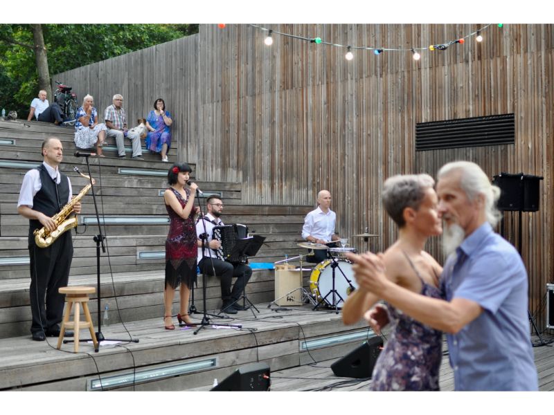 Na pierwszym planie para tańcząca do muzyki. W tle zespół muzyczny i architektura SDK