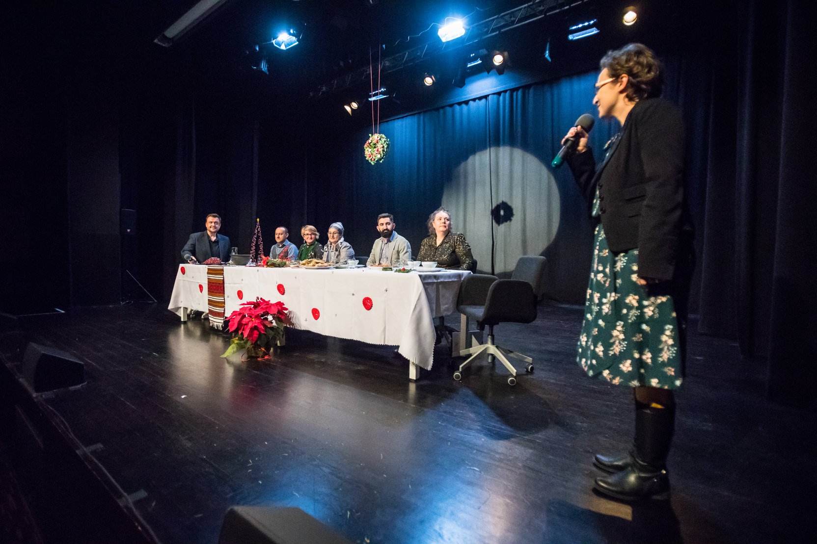 Na zdjęciu koordynatorka wigilii witająca gości - w tle biały stół wokół którego usiedli warszawiacy wielu narodowości