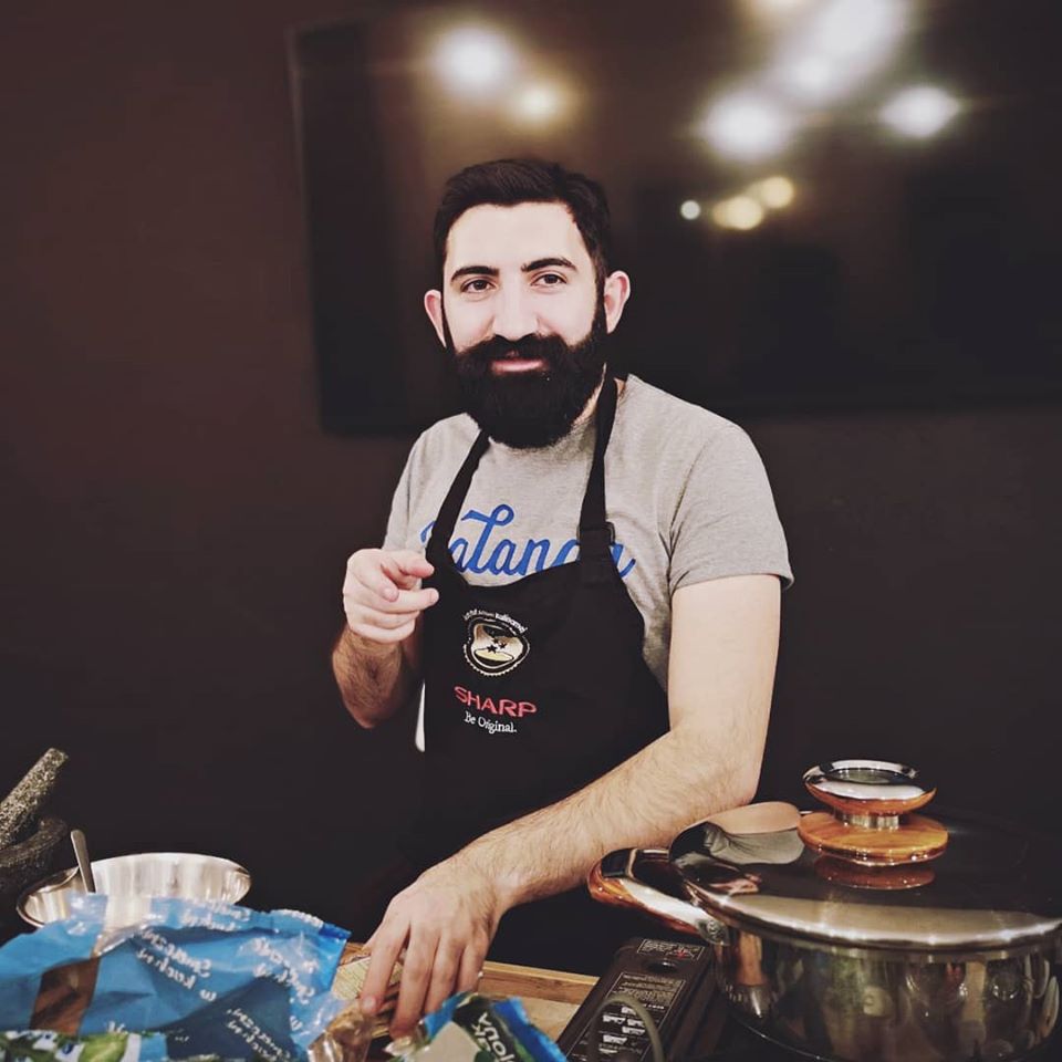 Na zdjęciu brodaty mężczyzna z fartuchu kucharskim