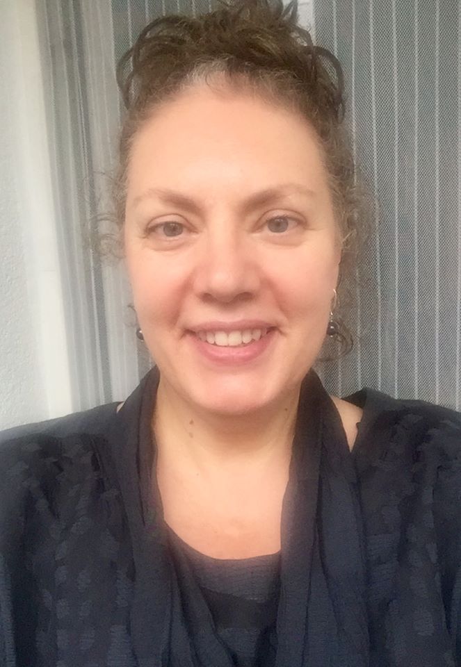 Potrtret kobiety ze spiętymi włosami, uśmiechnięta, w tle szare tło