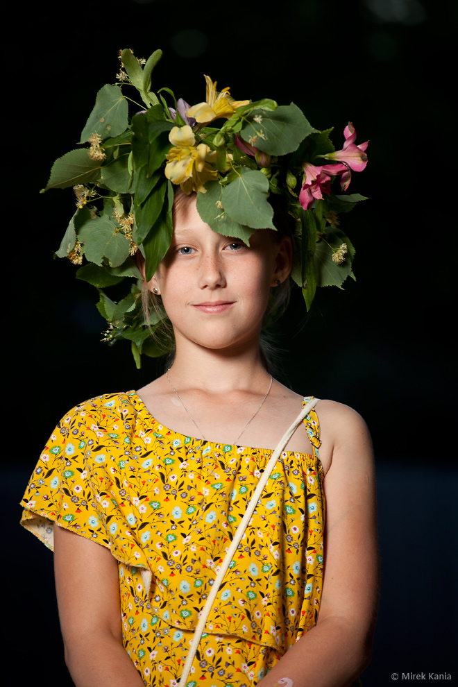 Na zdjęciu portretowym widoczna jest młoda dziewczynka w wianku na ciemnym tle.