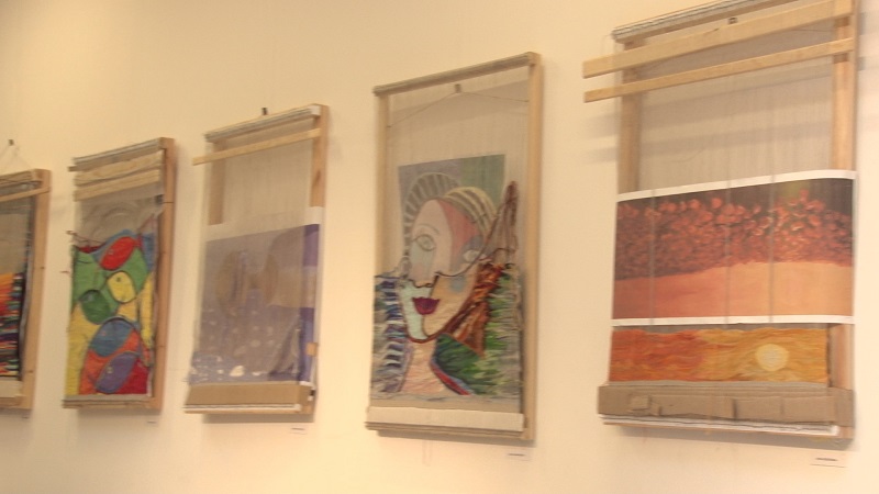 Część wystawionych dzieł - w tym niedokończonych - z pracowni tkactwa na jasnym tle.