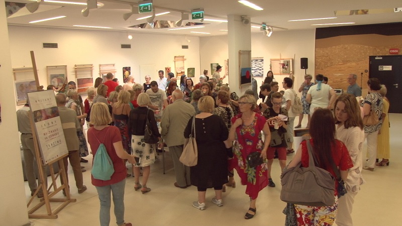 Zgromadzeni uczestnicy podczas jednego z wernisaży w foyer SDK. W tle wystawione prace uczestników.