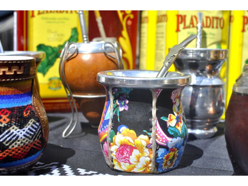 Zbliżenie na kolorowo zdobione zestawy do picia yerba mate. W tle żółte tło