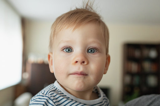 Na zdjęciu widoczny portret małego chłopca. Blond włosy oraz niebieskie oczy. Zdjęcie wykonane w domowej scenerii.