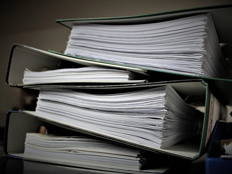 Zdjęcie segregatorów z dokumentami. Segregatory leżą jeden na drugim. Bliskie ujęcie