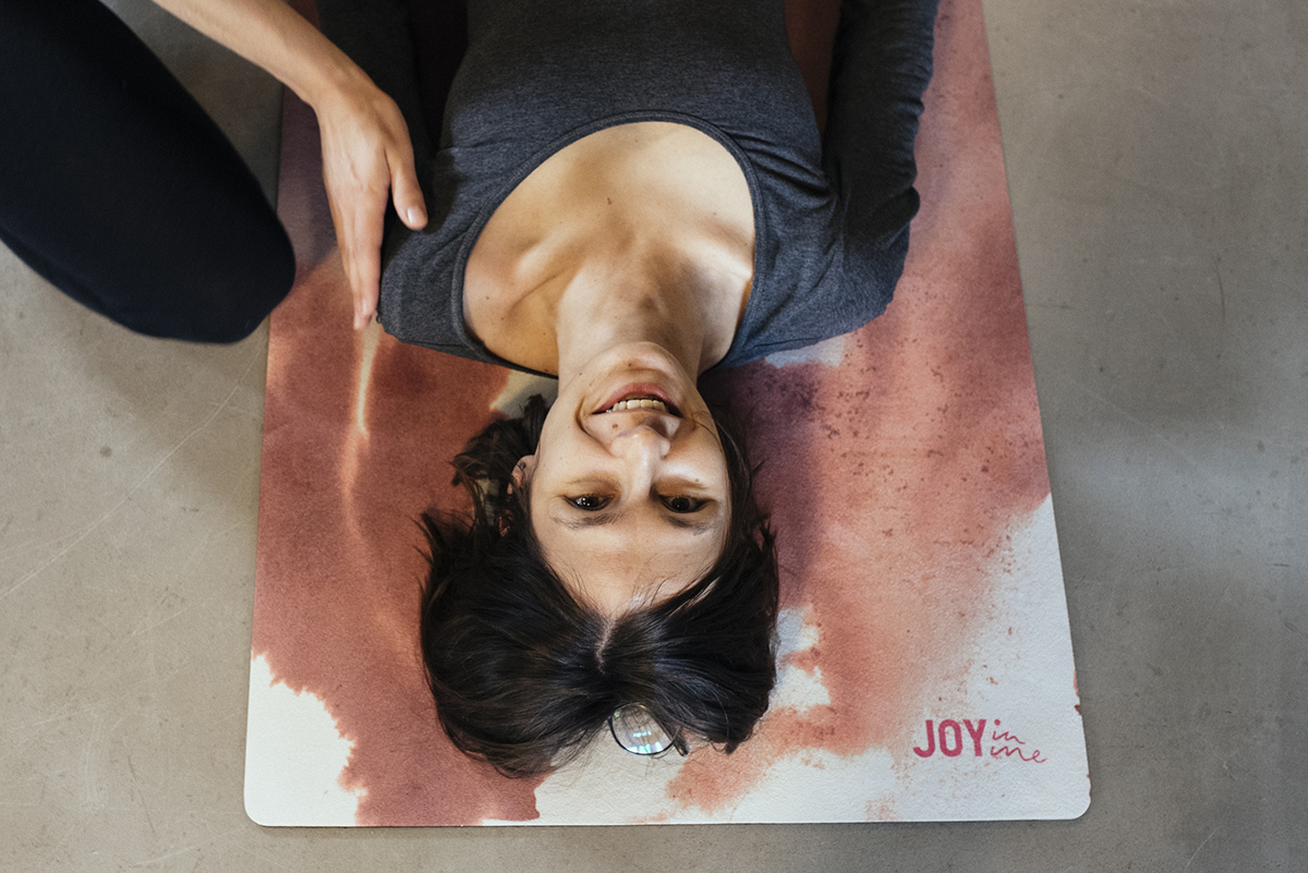 Rama przyciągająca uwagę odbiorcy: spojrzenie z góry na kobietę leżącą na biało-czerwonym malowidle, jej ramię trzyma dłoń kogoś spoza kadru. Fot. Zuzanna Jach