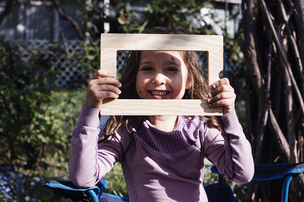 Rama w ramie: Kilkulatka przykłada do twarzy ramkę w kształcie prostokąta, śmieje się. Fot. Zuzanna Jach