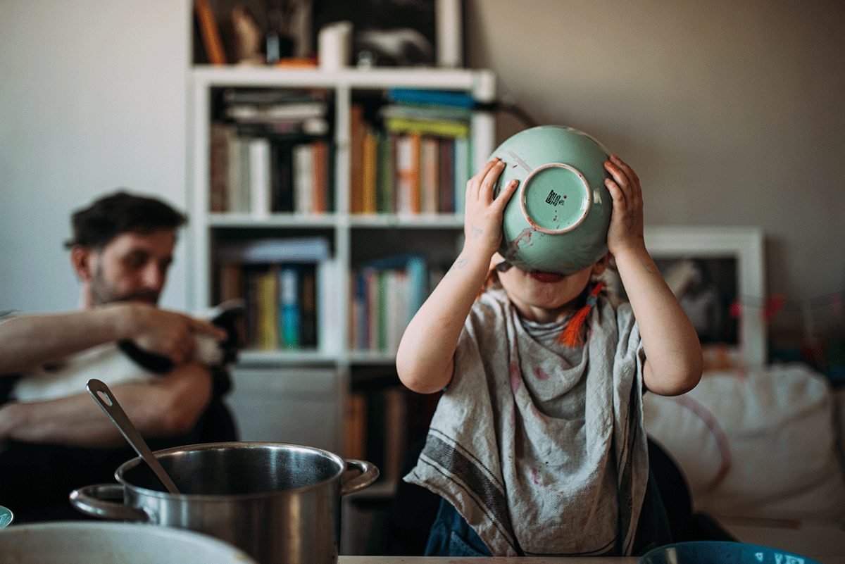 Na zdjęciu widać 4-letnią dziewczynkę po prawej stronie kadru, która pije zupę z miseczki i ma przewiązaną wokół szyi ściereczkę, po lewej w tle widać mężczyznę. fot. Agnieszka Mocarska