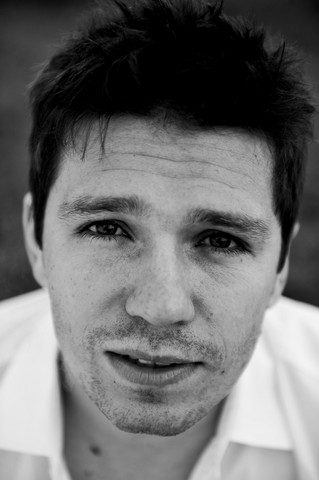 Czarno-biały portret mężczyzny. Czarne włosy i biała koszula. fot. Justyna Chowaniak