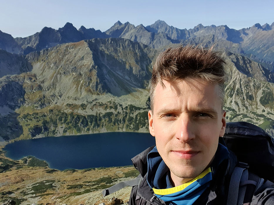 Zdjęcie portretowe Tomasza CHodkiewiczna na tle gór.