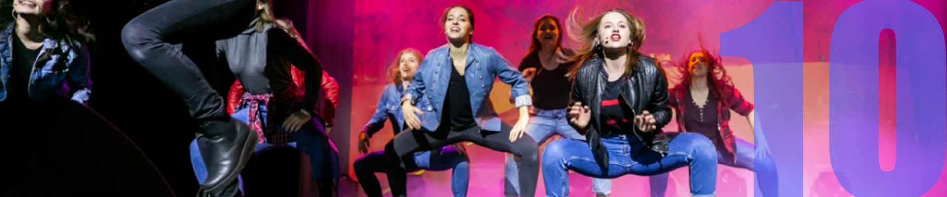 Zdjęcie:  grupa kilku dziewcząt w tanecznym ruchu na scenie. Dziewczyna na pierwszym planie podskakuje z gitarą w rękach. Fot. Weronika Pawłowska - Ciągło