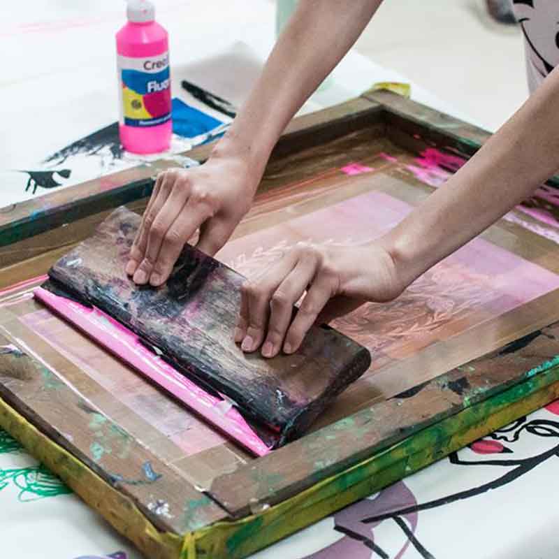 Ręce postaci wykonującej raklą odbitkę na sicie do sitodruku. Fot. Dominika Dzieniszewska