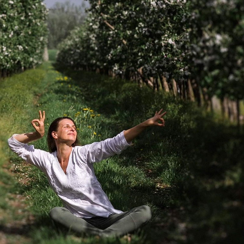 Fragment postaci siedzzącej w pozycji kawiatu lotosu, w dłoni trzyma zielony listek.