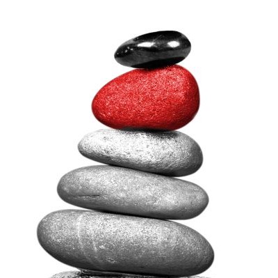 Na grafice pionowo ułożonych pięć kamieni - ułożone od największego do najmniejszego - każdy w innym rozmiarze i kolorze. Tworzą kształt przypominający trójkąt. Trzy największe są w odcieniach szarości, czwarty hest czerwony, a najwyżej położony jest czarny.