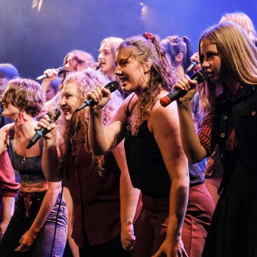 Grafika przedstawia okrągłe kamienie poustawiane jeden na drugim, w stosie. Od największego do najmniejszego. Szczytowe kamienie w dwóch kolorach - czerwonym i czarnym. Obok informacja tekstowa o tytule i dacie wydarzenia.