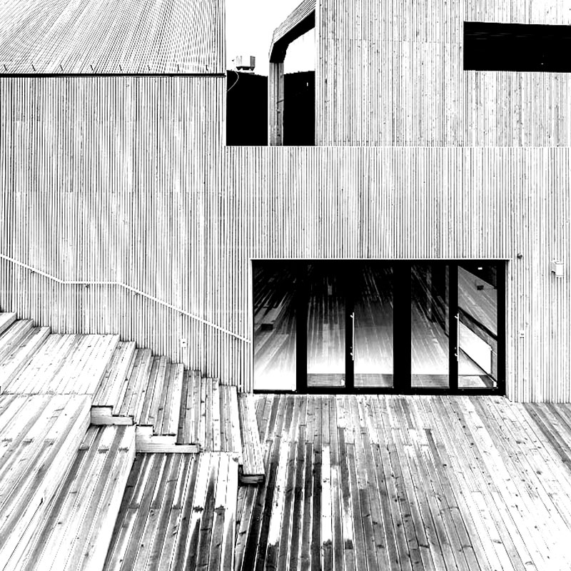 Na zdjęciu fragment architektury SDK. Drewniany amfiteatr oraz wejście główne do budynku SDK. Zdjęcie czarno-białe. 