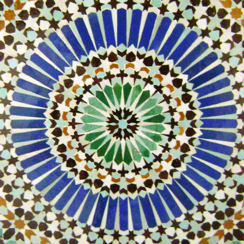 Zdjęcie fragmentu mozaiki ułożonej centalnie w okręgi z geometrycznych elementów.