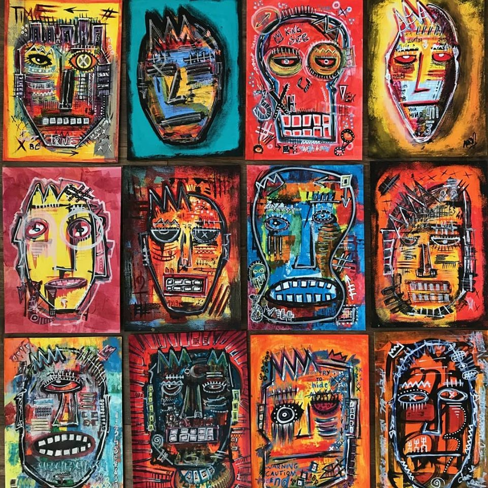 Na grafice obrazy artysty. Zestaw 12 kolorowych, abstrakcyjnych masek ułożonych rzędami, po 4 w rzędzie.