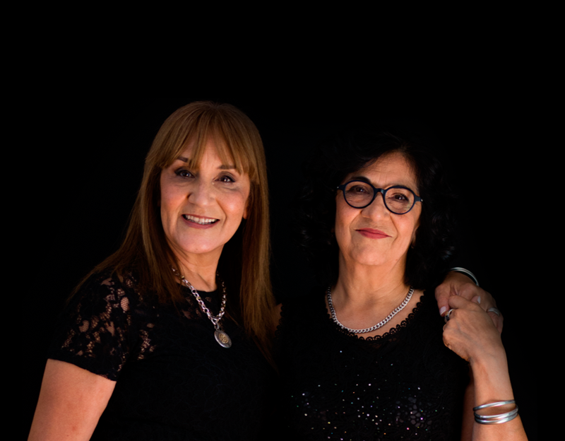 Na zdjęciu dwie solistki zespołu. Półportret dwóch kobiet na czarnym tle.