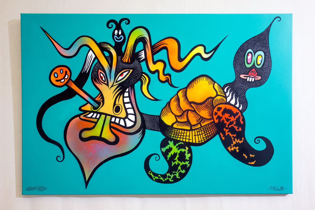 Abstrakcyjne, kolorowe zwierzę. Połączenie żółwia z głową przypominającą głowę byka. Ze stworzenia wystają inne głowy. Wszystko na niebieskim tle. 