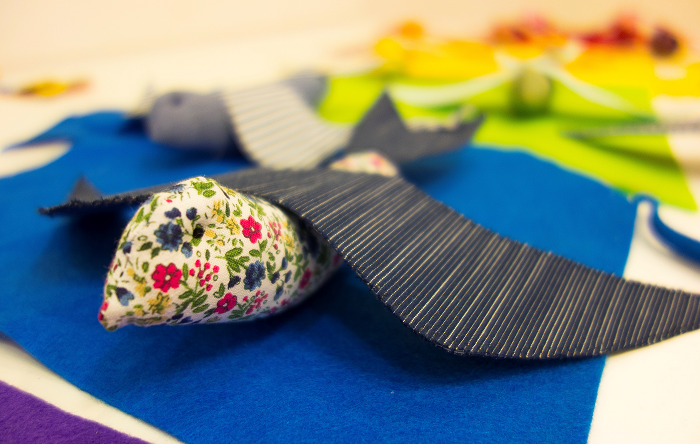 Zdjęcie przedstawia zbliżenie na wykonane już kolorowe ptaki patchworkowe, będące częścią wspominanej instalacji. Tło rozmyte.