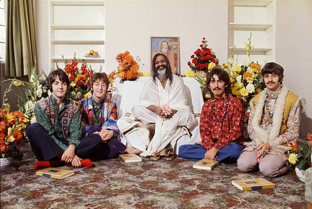 Na zdjęciu grupa oósb w pokoju siedząca na podłodze: w środku, ubrany w jasne szaty guru Maharishi Mahesh Yogi, po jego prawej stronie Paul McCartney i John Lennon; po lewej George Harrison i Ringo Starr.